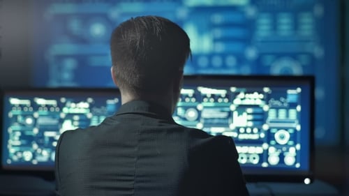 Back View of Programmer Working on Computer in Dark Digital Office