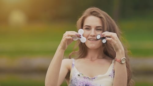 Une jolie jeune fille vêtue d'une robe d'été tient des fileuses tournantes dans ses mains. La nature.
Été