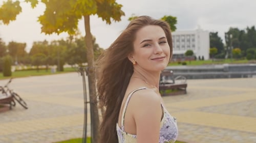 A Charming Sensual Young Girl in a Summer Dress Is Walking Along the Park in the Center of the City