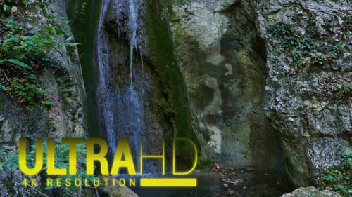 Small Waterfall Cascading in Green Rocky Grotto