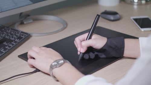 Person Using Stylus on Tablet at Desk