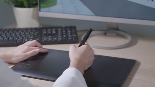 Hands Using Stylus on Graphics Tablet at Workplace
