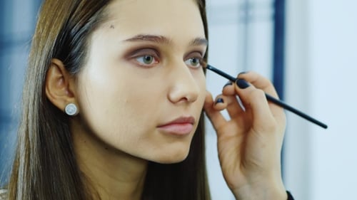 Woman having eye makeup applied with brush