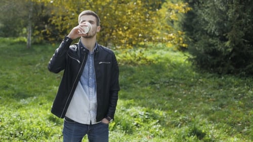 Handsome Male Model Drinks Coffee in a Fresh Autumn Park