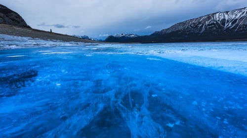 Icy Blue Lake Under Mountainous Cloudy Sky