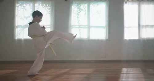 Imagens em câmera lenta de um menino praticando artes marciais dentro de um dojo