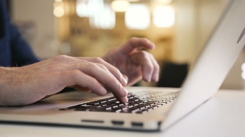Hands Typing on Silver Laptop in Office