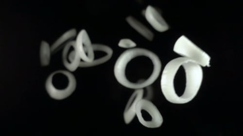 Fresh Onion Rings Floating on Black Background
