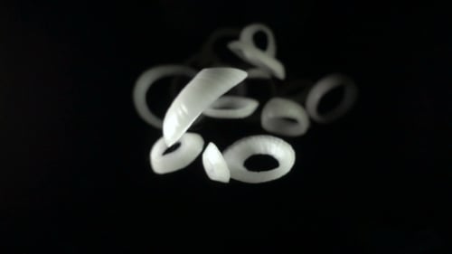 Onion Rings Falling in Slow Motion on Black