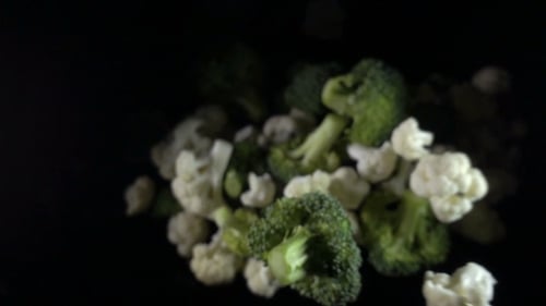 Blumenkohl fällt in die Luft auf schwarzem Hintergrund