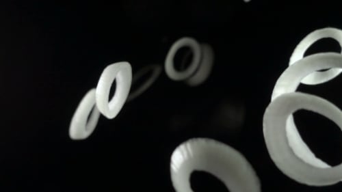Onion Rings Falling on a Black Background