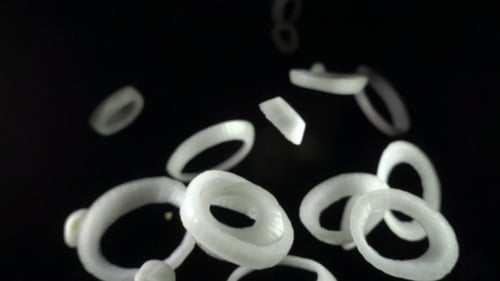 Crispy Sliced Onion Rings Falling Against Black Backdrop