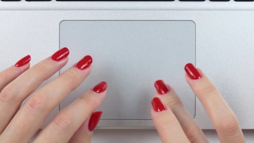 Woman's hands with red manicure on laptop touchpad
