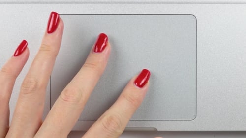 Woman's Left Hand with Red Manicure Using and Clicking a Trackpad. Top View,