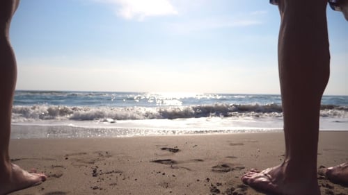 Young Man and Woman Standing on the Shore and Enjoying Sea at Sunrise