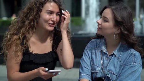 Young Women Laughing at Phone in Urban Setting