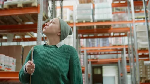 Female Warehouse Manager Walking along Shelves