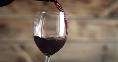 Pouring Red Wine Into a Glass Indoors