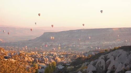 Hot Air Balloons Floating Over Mountainous Landscape at Sunrise