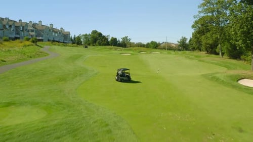 Golf course flyover with fairway green sand traps and golf cart