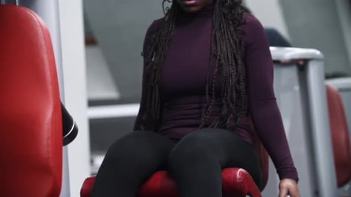 Uma mulher afro-americana malhando em uma academia com um equipamento de exercícios para as pernas