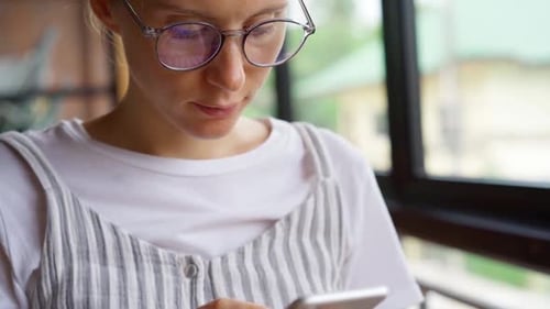 Woman Using Smartphone Indoors by a Window