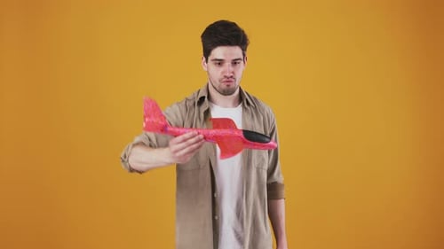 Enthusiastic Young Adult Throws Toy Airplane