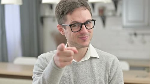 Smiling Young Adult Pointing at Camera Indoors