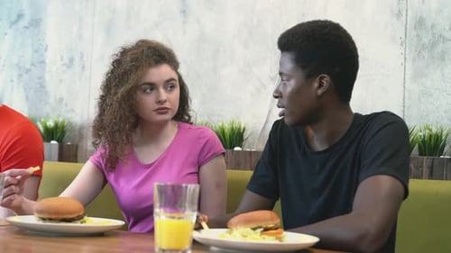 Young Adults Eating Burgers Together at Restaurant