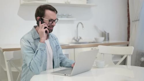 Cheerful Beard Young Man Talking on Smartphone in Office
