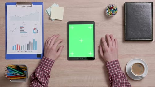Top View of a Man Tap Multiple Times on the Right Bottom Corner of a Green Screen on Tablet