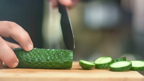 Close Up Male Chef Hands Cutting Fresh Raw Green Cucumber on Wooden Board