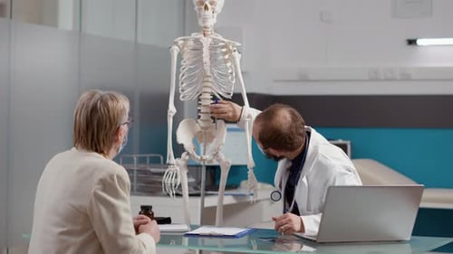 Arzt zeigt auf menschliches Skelett zur Erklärung der Osteopathiediagnose