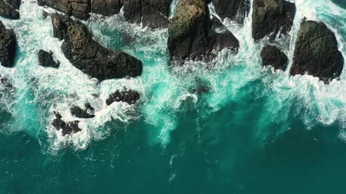 ocean blue waves break on high cliff of a rocky mountain.