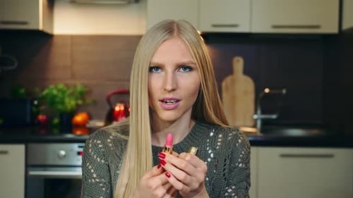 Blonde Woman Applies Pink Lipstick in Kitchen