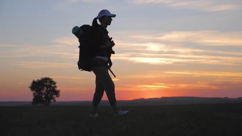 Backpacker Walking Across Rural Field at Sunset