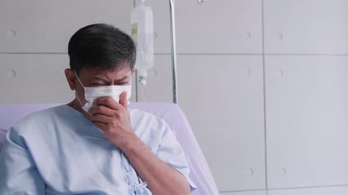 Adult Man Coughing in Hospital Bed Wearing Mask