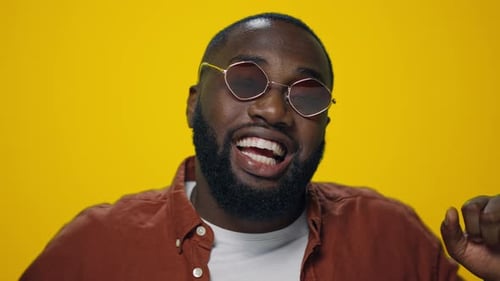 Excited Man Dances Vigorously Against Yellow Background
