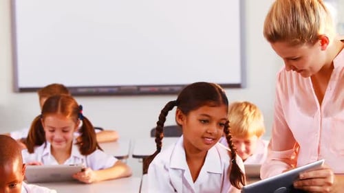 Teacher Helping Students with Tablets in Classroom