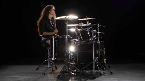 Woman Playing Drums in a Dark Room