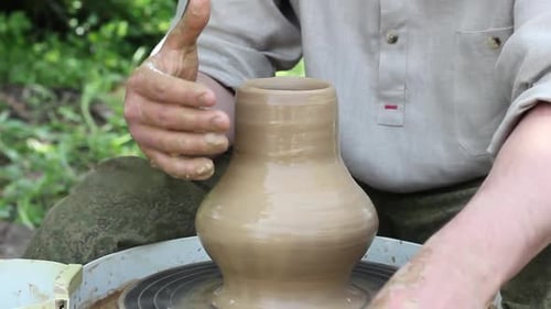un potier caucasien sculpte un grand pot en argile sur un cercle en rotation