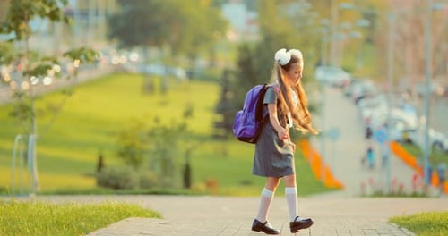 Kleines Mädchen aus einer Grundschule in einem Park in den Sonnenstrahlen