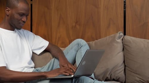 Young Adult Using Laptop on Couch at Home
