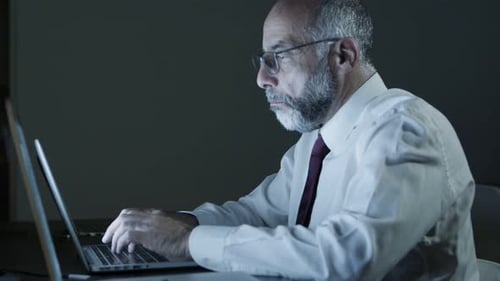 Tired Businessman Using Laptop in Dark Office