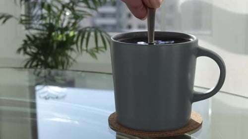 Eine große Tasse Kaffee auf dem Tisch rühren Sie das Getränk mit einem Löffel um