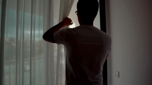 Man Opens Curtains and Walks Onto Balcony