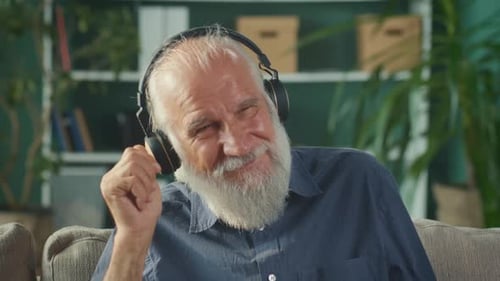 Smiling Senior Man with Headphones Listens to Music