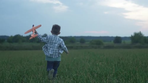 A Boy Launches an Airplane Outdoors in a Field