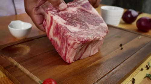 Chef cook season fresh chunk of deli piece of beef with sea salt and grounded spicy peppers.