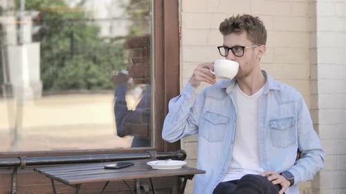 Young Adult Drinks Coffee at Outdoor Table